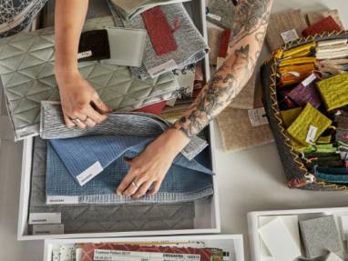 Overhead photo showing a person's arms as they look through Designtex upholstery samples