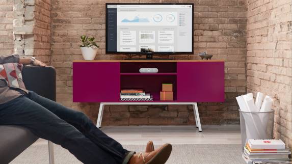 A person relaxes on a sofa next to a pink-colored Bivi Trunk with a monitor placed on top of it