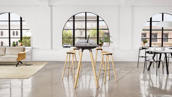 A Potrero415 Light table with wood legs and black top and Enea Cafe wood stools around it