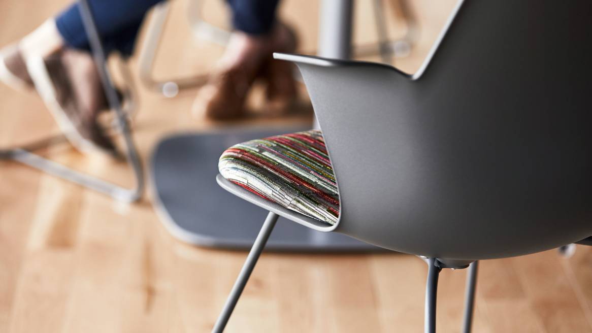 A close-up photo of the back of a gray Node X base chair with multi-colored seat upholstery