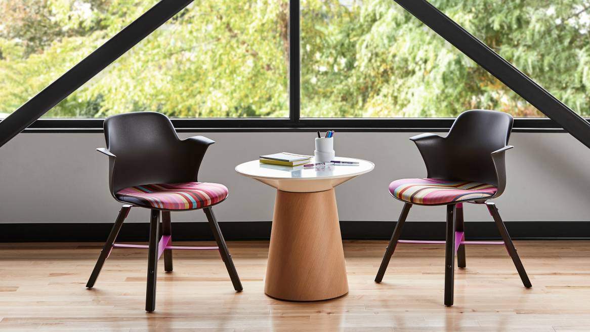 Two Node chairs with wood legs and striped, multi-colored seat upholstery are shown next to a Campfire Paper Table