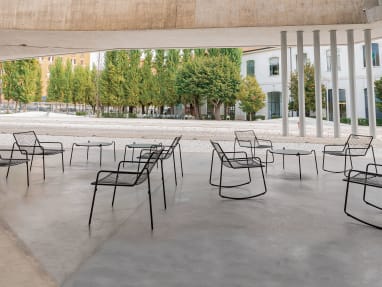 A variety of black EMU Rio R50 chairs and tables in an outdoor space.