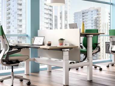 Ology height adjustable benching next to a window and shown with Gesture desk chairs, Universal Center Screen, and SOTO Personal Console