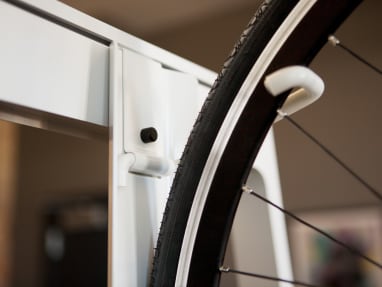 Close-up photo of a white Turnstone Bivi Bike Hook with a black bike tire hanged.