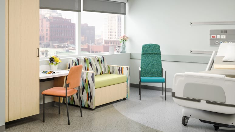 inside an hospital room with an orange sorrel chair in front of a table, a 1-person sofa next to it