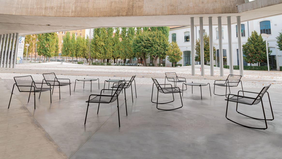 A variety of black EMU Rio R50 chairs and tables in an outdoor space.