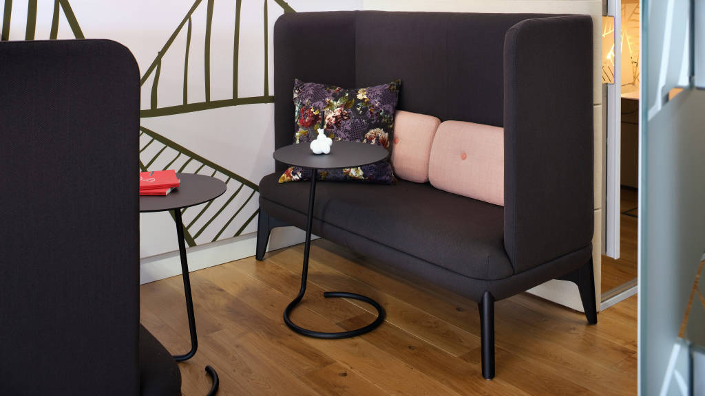 Black Orangebox sofa with pink pillows and a personal table in front of it.