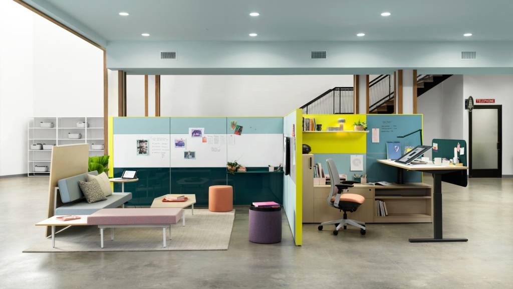 Setting with blue and yellow walls, Adjustable desk, pink office chair, blue sofa.