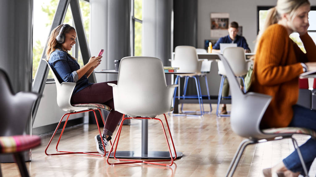 student looking at her cellphone while seated on a Node chair